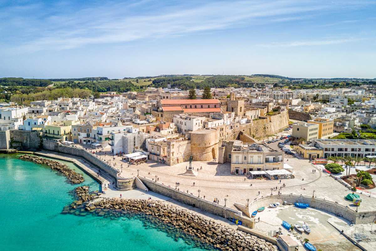 Spiaggia sabbiosa di Otranto, bambini che giocano vicino all’acqua, sfondo della città antica di Otranto, atmosfera familiare